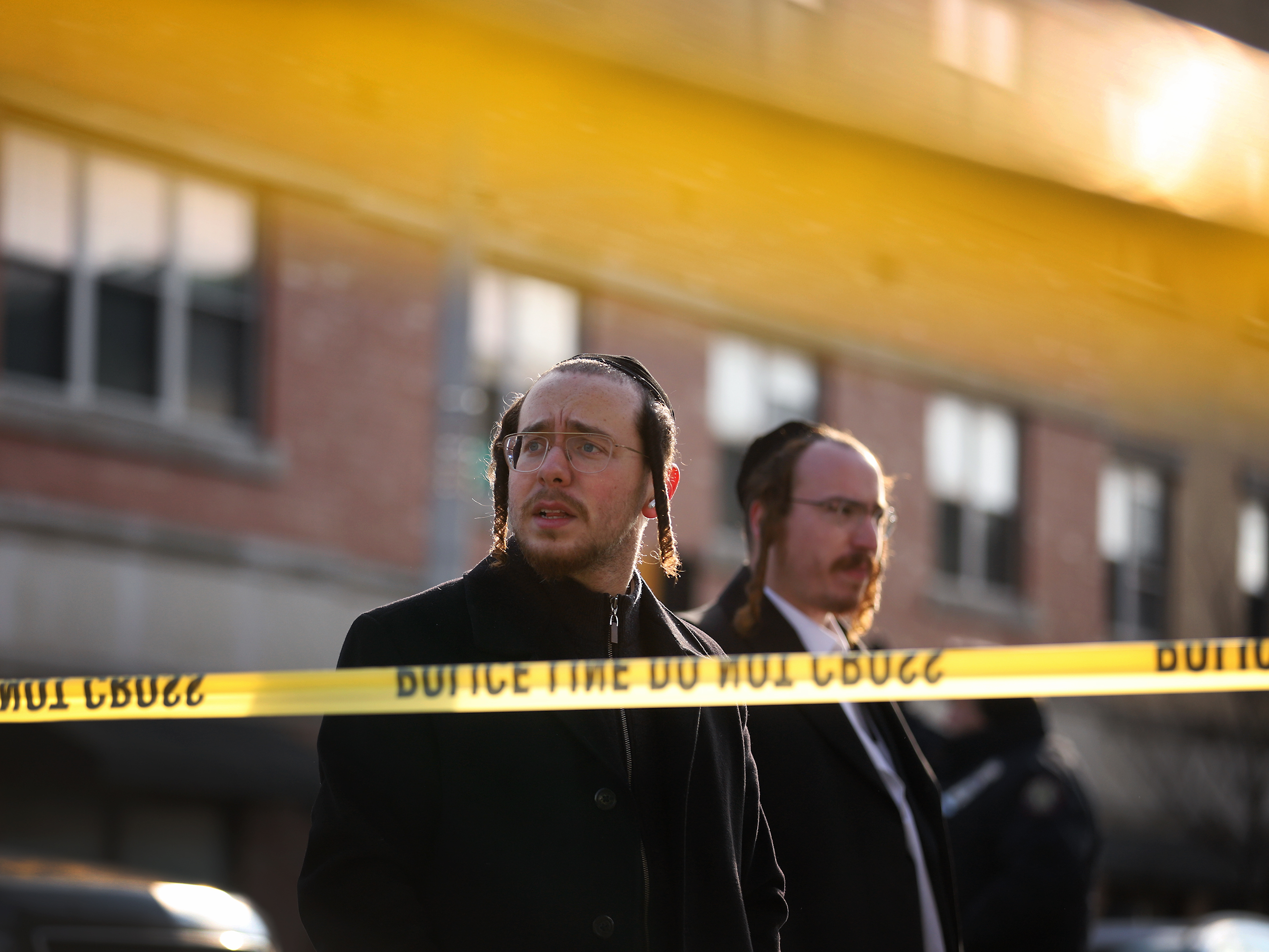 caption: Two men look on as members of Jersey City's Jewish community gather outside the J.C. Kosher Supermarket on Wednesday. Six people, including the suspects and a local police officer, died Tuesday in what officials called a "targeted attack."