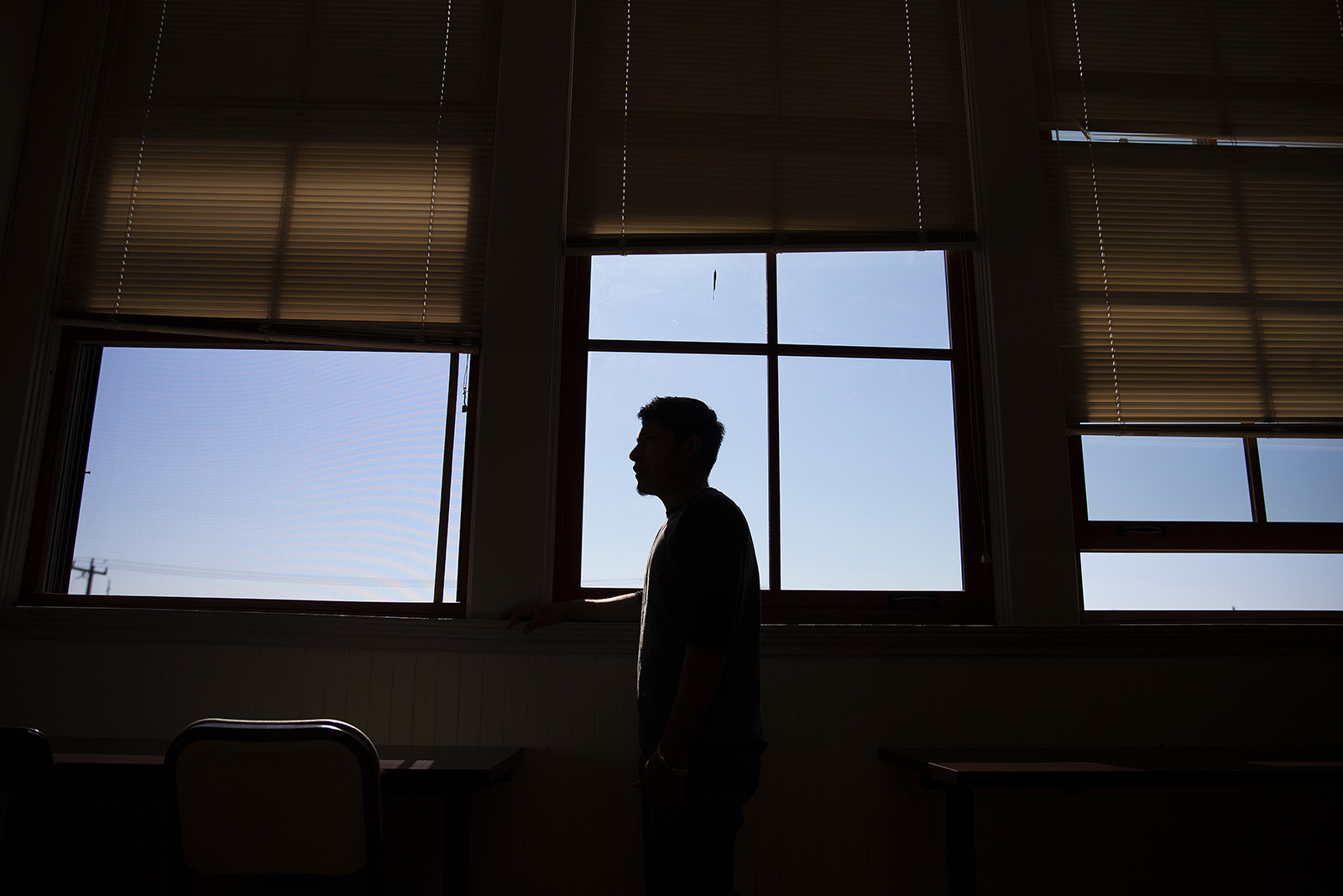 caption: Manuel stands next to a window in his English class. 