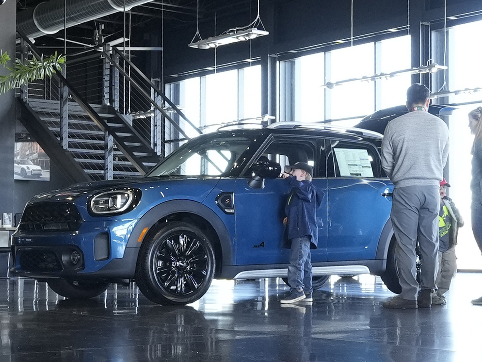 caption: Potential buyers look at a 2023 Cooper Countryman S sports-utility vehicle on the floor of a Mini dealership on Friday, Feb. 17, 2023, in Highlands Ranch, Colo.