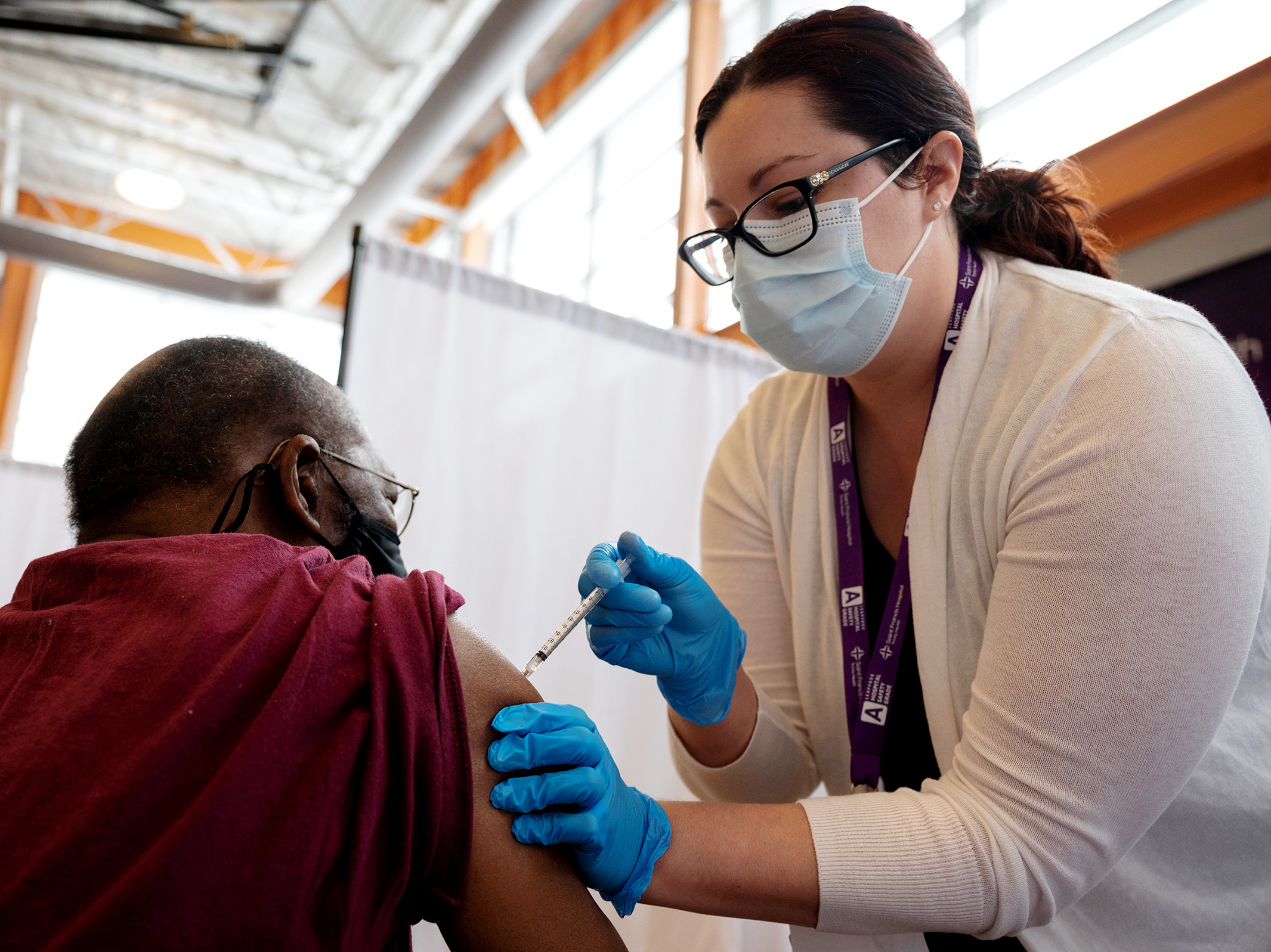 caption: Trinity Health RN Kayla Bennett gives Hartford, Conn., resident James Watts his first dose of the COVID-19 vaccine at a neighborhood vaccine clinic at the at the Parker Memorial Community Center.