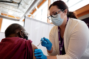 caption: Trinity Health RN Kayla Bennett gives Hartford, Conn., resident James Watts his first dose of the COVID-19 vaccine at a neighborhood vaccine clinic at the at the Parker Memorial Community Center.