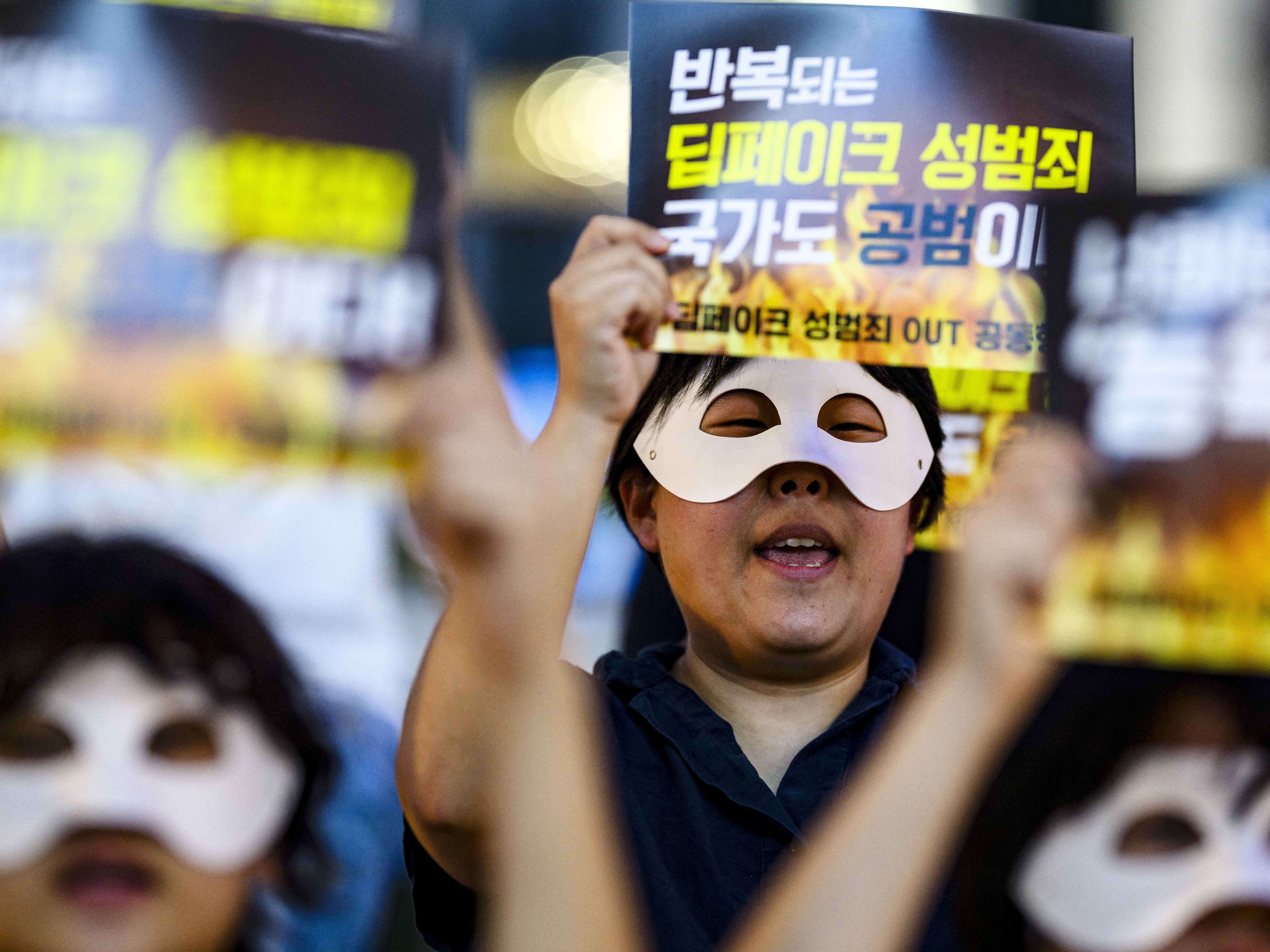 caption: Activists wearing eye masks hold posters reading "Repeated deepfake sex crimes, the state is an accomplice too," during a protest against sexually abusive deepfakes in Seoul, South Korea, on Aug. 30.