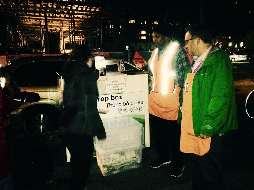 caption: At 7:44 p.m. Tuesday, lines of cars waited outside the Ballard library to drop of election ballots.