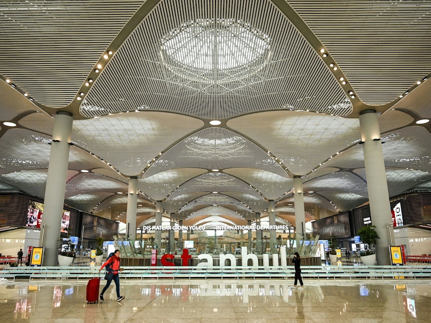 caption: Passengers walk in the new hall of Istanbul Airport on the first day after moving from Ataturk International airport on April 6, 2019, in Istanbul. Many Russian men (not pictured) have been buying up tickets for Turkey since their government issued a draft to fight in Ukraine.