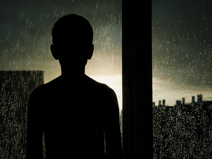 Child looking out the window on a rainy day.