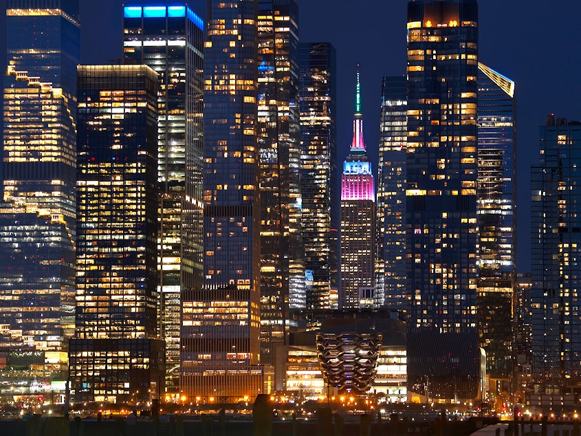caption: The Empire State Building is lit in pastel colors to mark Easter as it stands between the towers of Hudson Yards in New York City on March 31.