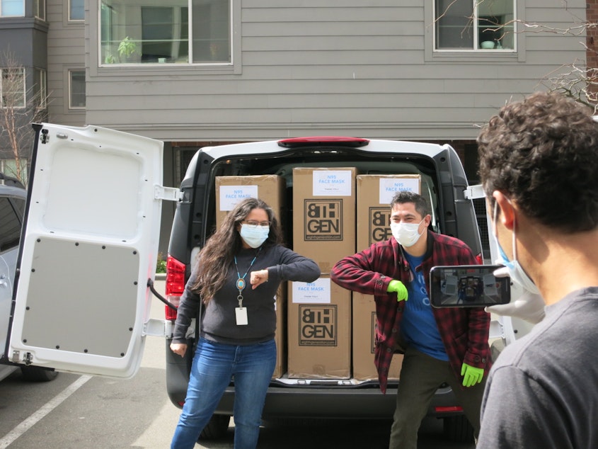 caption: Seattle Indian Health Board CEO Esther Lucero and Eighth Generation CEO, Louie Gong, pose for a photo with the company’s donation of masks. 