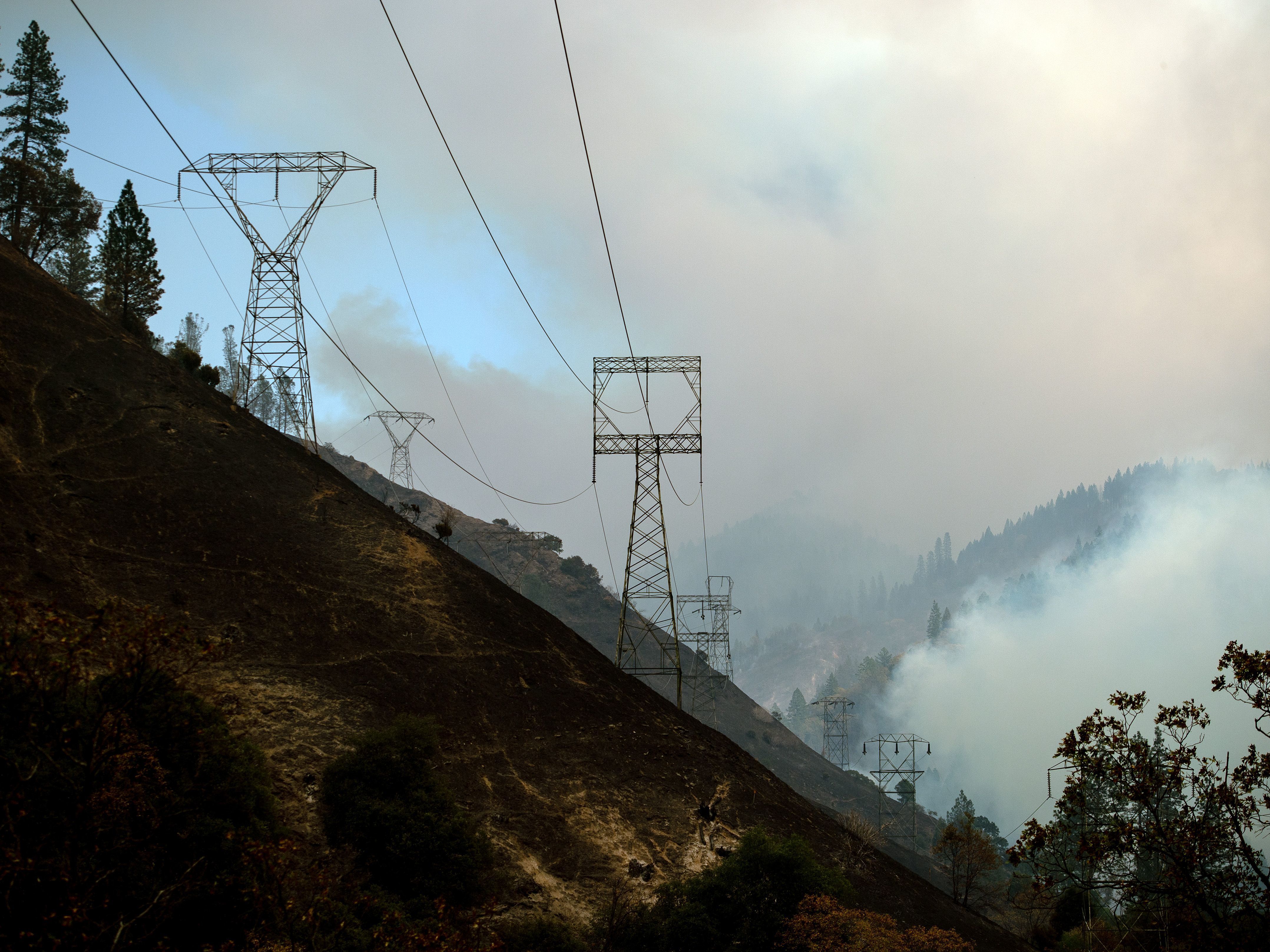 caption: Power lines are seen through smoke from the Camp Fire near Pulga, Calif., on Sunday.