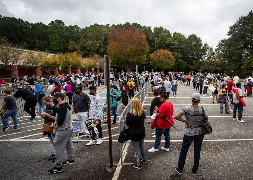 caption: Hundreds of people wait in line for early voting on Monday, Oct. 12, 2020, in Marietta, Georgia. Eager voters have waited six hours or more in the former Republican stronghold of Cobb County, and lines have wrapped around buildings in solidly Democratic DeKalb County. (Ron Harris/AP Photo)