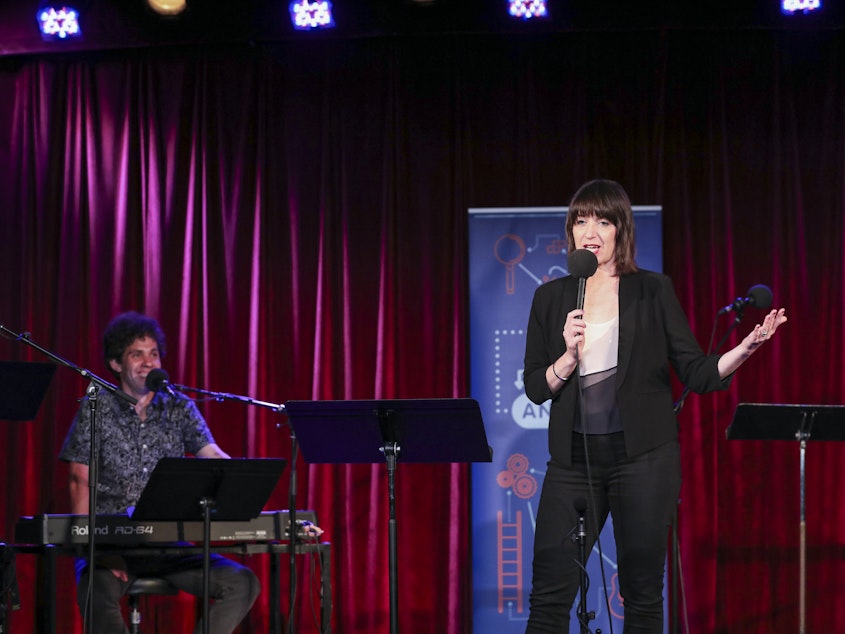 caption: Ophira Eisenberg performs alongside guest house musician Julian Velard on<em> Ask Me Another</em> at the Bell House in Brooklyn, New York.