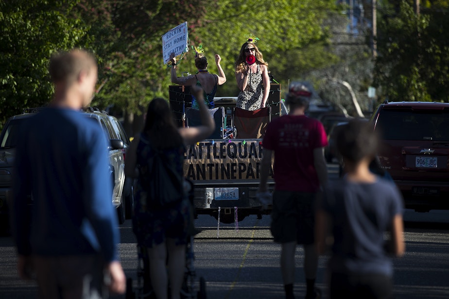 caption: Wallingford residents follow along as the Seattle Quarantine Parade, including Lindsey Hornickel, left, and Darcy Newby, right, drives through the neighborhood on Friday, May 8, 2020, in Seattle.