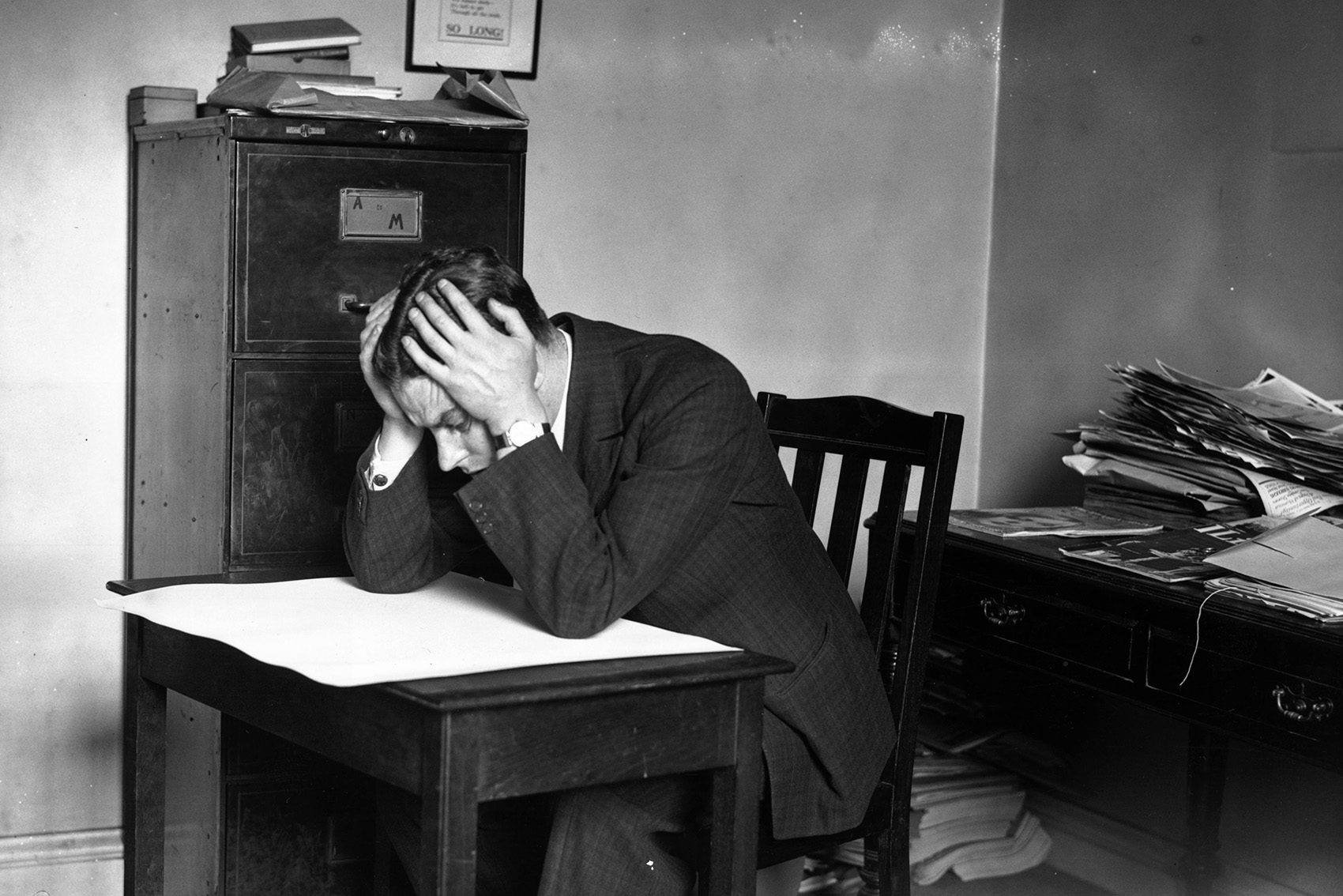 caption: A man staring at blank sheet of paper with his head in his hands.  (Topical Press Agency/Getty Images)