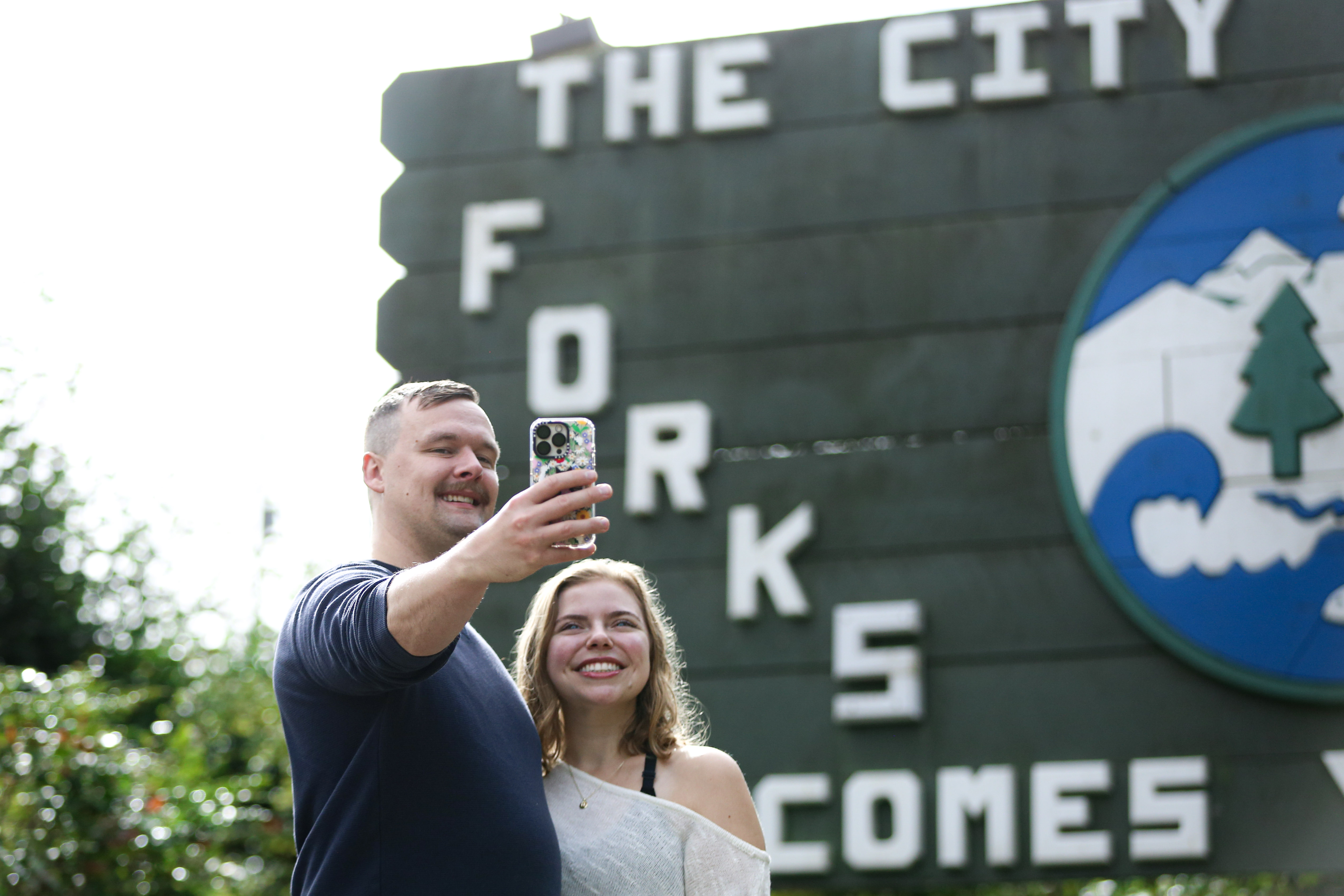 caption: Matthew Miller (left) and Kerigan Fabery (right) take a selfie in front of the sign that welcomes visitors to the city of Forks, Washington. They were among hundreds of visitors who came to town to celebrate the 20th anniversary of the "Twilight" series.  