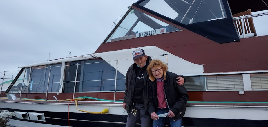 caption: Ian and Becky Thompson with their boat at the Bremerton Marina. They've been living in this boat for close a year.