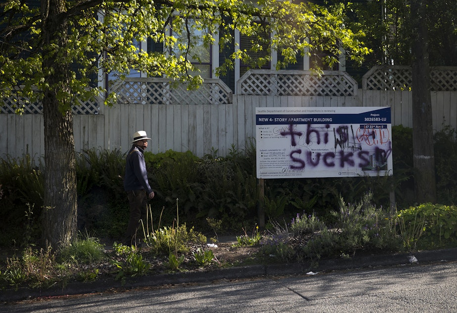 caption: A pedestrian walks along East John Street near the intersection of 23rd Avenue East on Thursday, May 7, 2020, in Seattle.