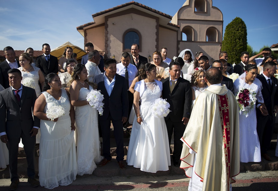 Alejandro Trejo, or Father Alex, arranges couples before a group portrait is taken by a wedding photographer in front of the church on Sunday, June 2, 2019, at Our Lady of the Desert Church in Mattawa.