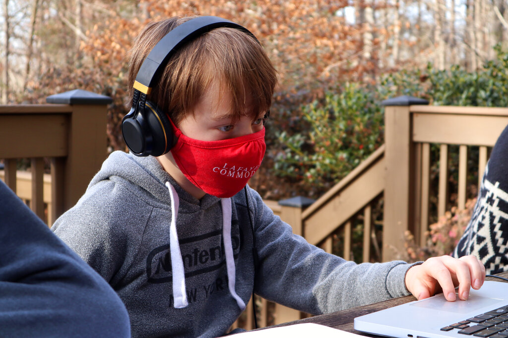 caption: Fourth grader Jess Atkins works on an online math lesson on his laptop at his home in Oxford, Miss., Friday, Dec. 18, 2020. (AP Photo/Leah Willingham)