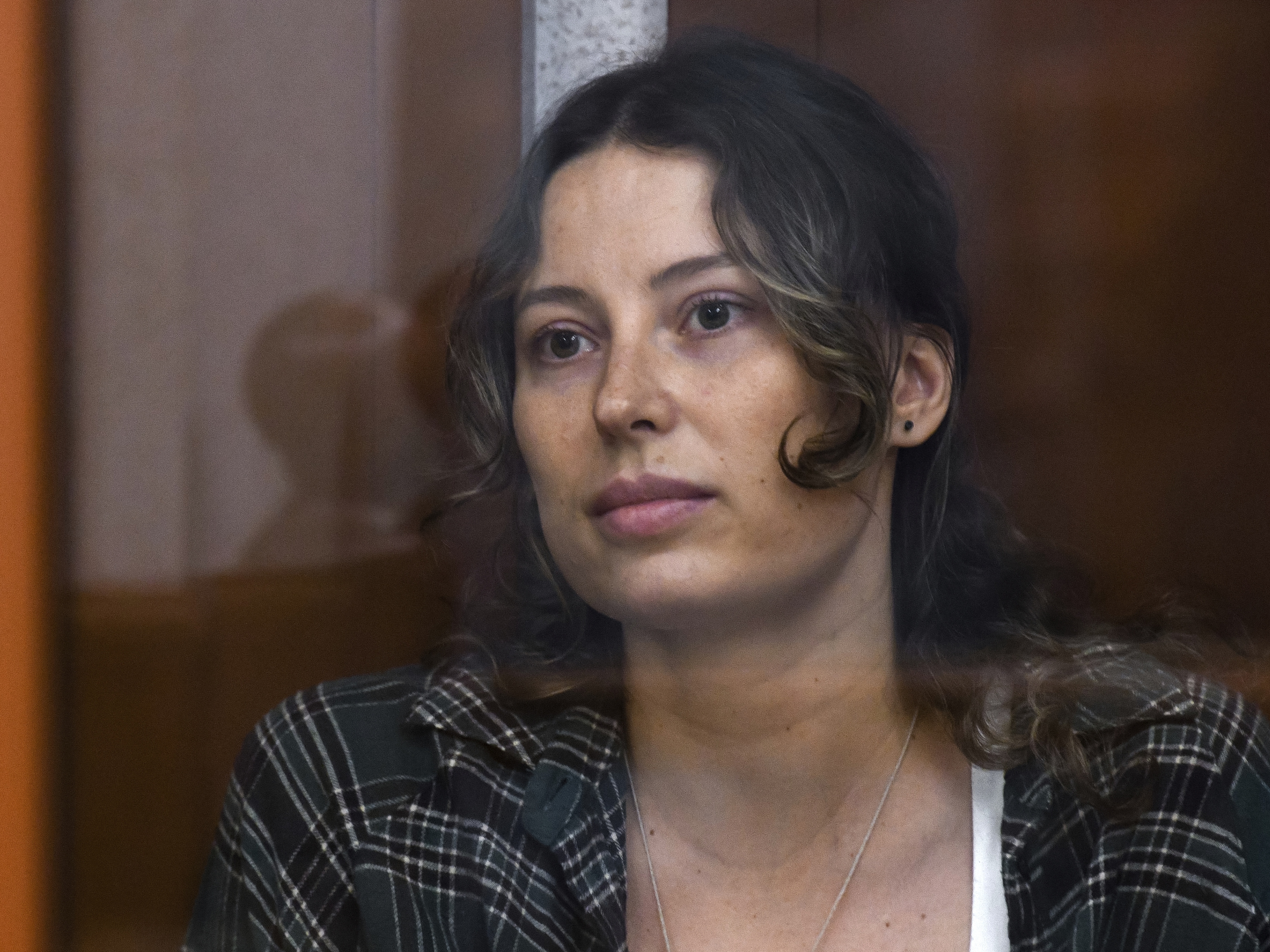 caption: Ksenia Karelina, also known as Khavana sits in a glass cage in a court room in Yekaterinburg, Russia, Thursday, June 20, 2024.