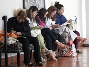 caption: In this photo, women fill out job applications at a JobNewsUSA job fair in Miami Lakes, Fla.