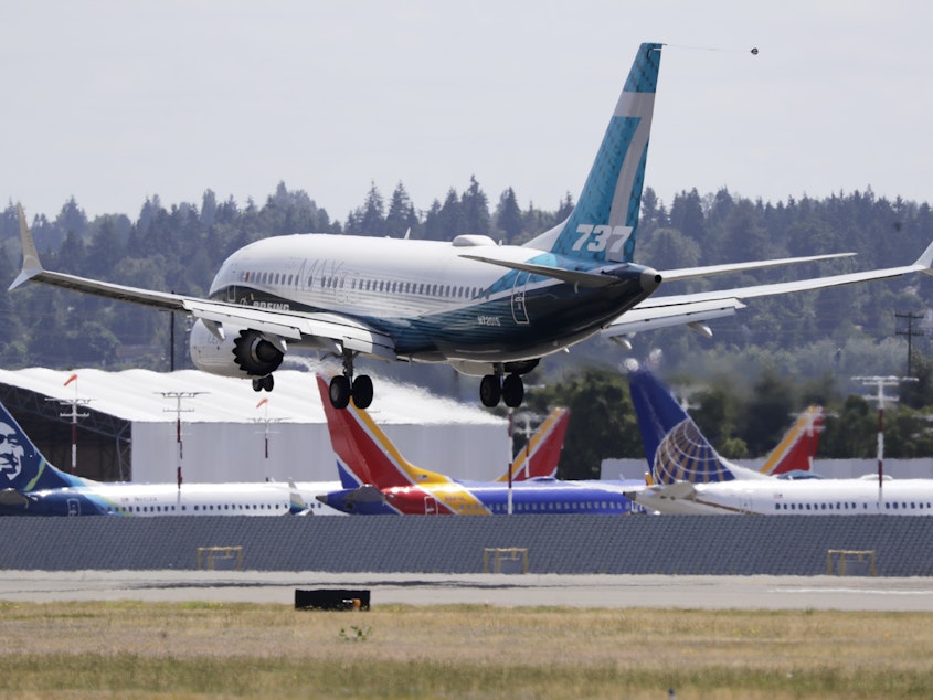 caption: A Boeing 737 Max heads to a landing past grounded Max jets at Seattle's Boeing Field, following a test flight in June. It was the first of three days of re-certification test flights that mark a step toward returning the aircraft to passenger service.