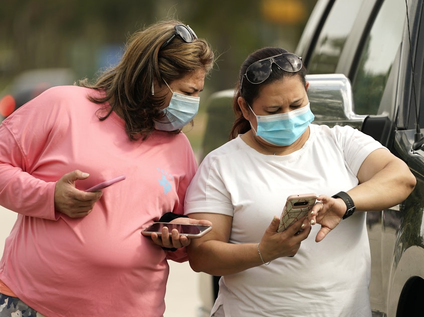 caption: Women wear masks in Houston on Wednesday. Harris County requires any business providing goods or services to require all employees and visitors to wear face coverings in areas of close proximity to co-workers or the public, at least through Aug. 26.