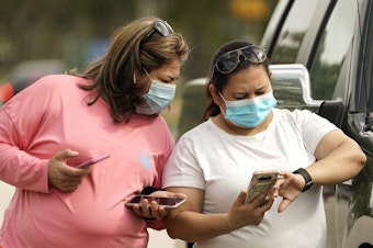 caption: Women wear masks in Houston on Wednesday. Harris County requires any business providing goods or services to require all employees and visitors to wear face coverings in areas of close proximity to co-workers or the public, at least through Aug. 26.