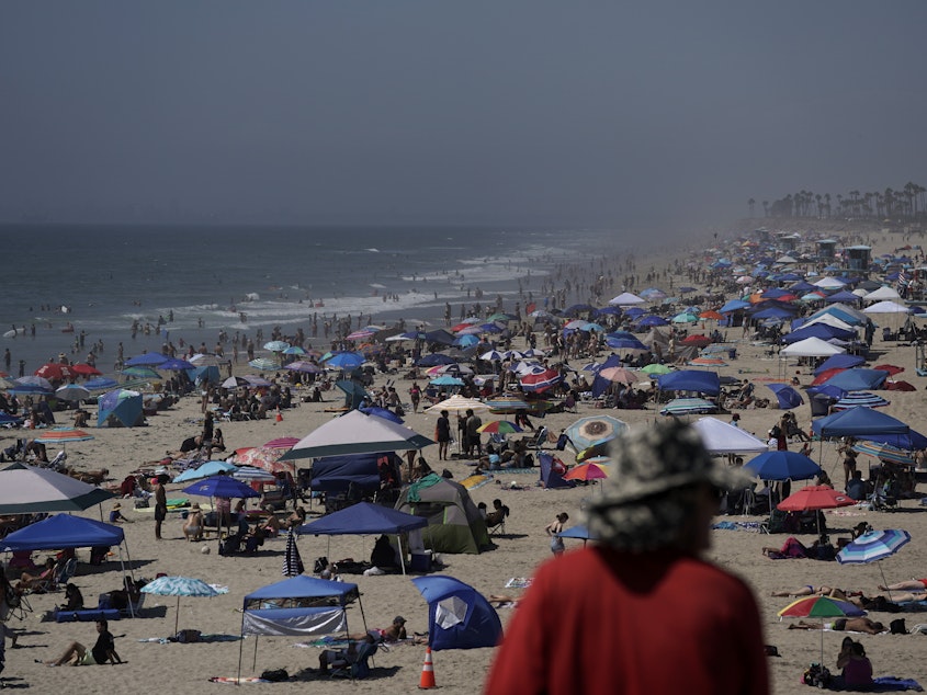 caption: People crowd the beach in Huntington Beach, Calif., over the long Labor Day weekend last year, months before COVID-19 vaccines were available. This year, the CDC is recommending that people who are not fully vaccinated stay home.
