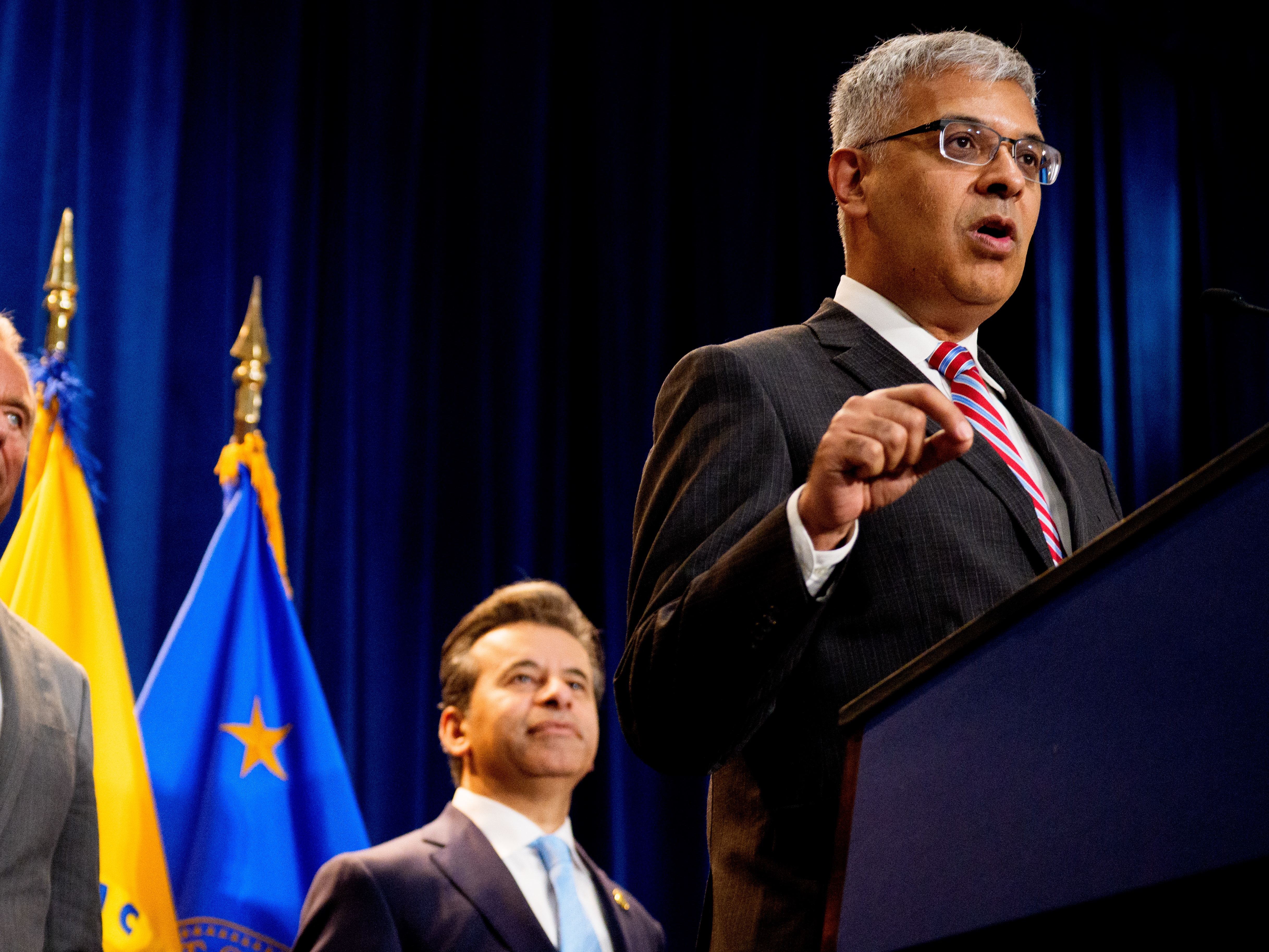 caption: NIH Director Jay Bhattacharya (right), accompanied by HHS Secretary Robert F. Kennedy Jr. (left) and FDA Commissioner Marty Makary (center), speaks during a news conference Tuesday at the Health and Human Services Department on in Washington, D.C.