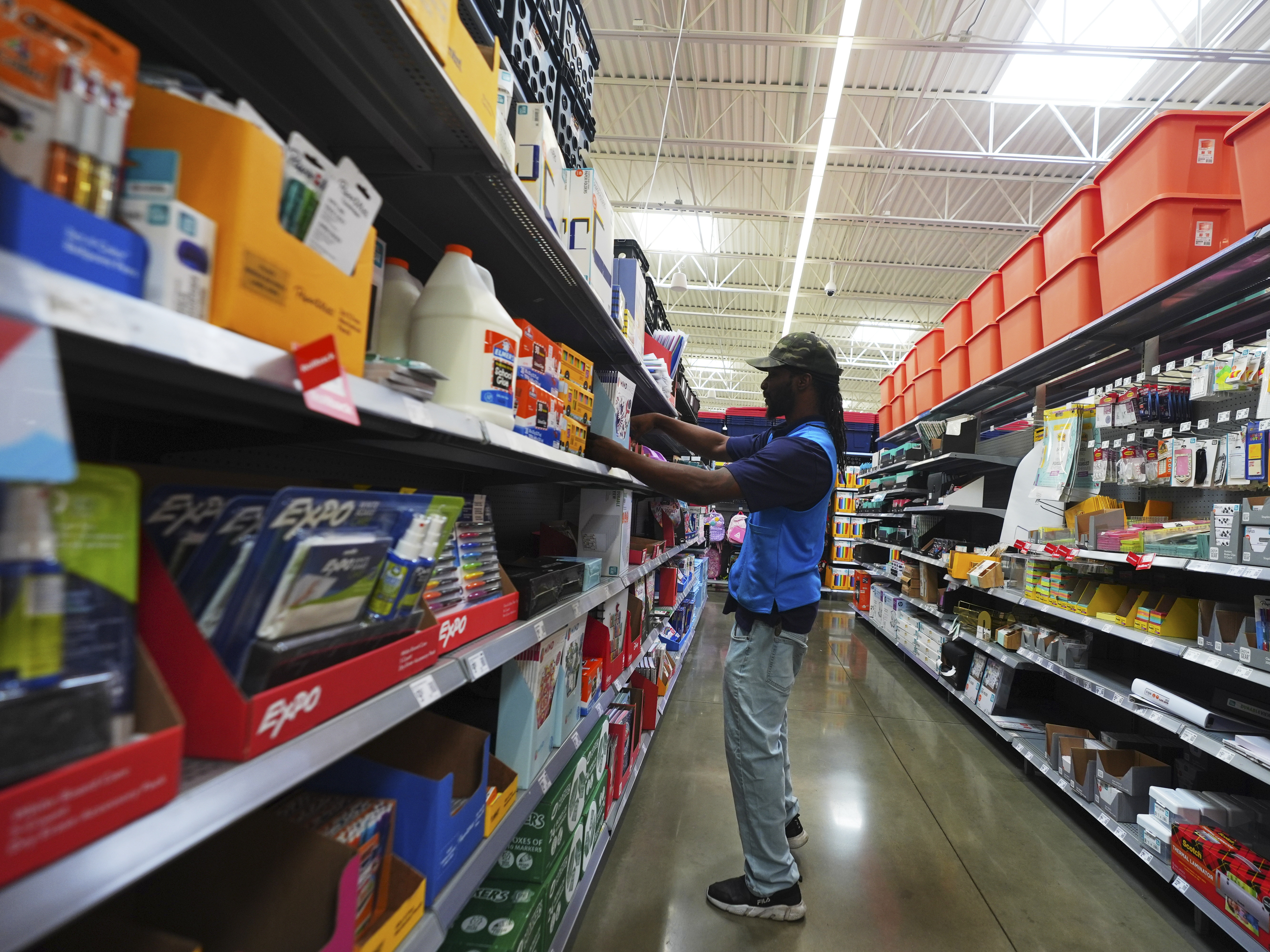 caption: Walmart employee Tim Taylor adjusts items for sale in the back-to-school section of a store in Dallas.