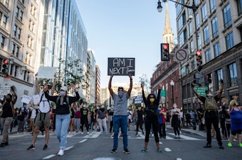 caption: Demonstrators in Washington, D.C., on Sunday hold signs as they protest the death of George Floyd.