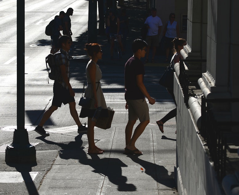 caption: People walk along sun-baked University Way Northeast in Seattle on Friday.