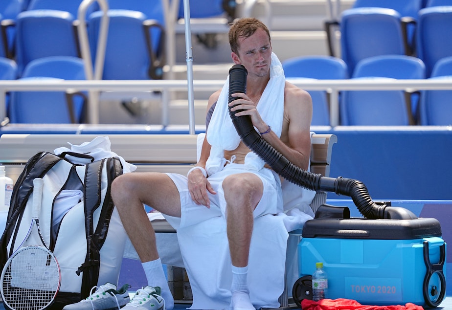 caption: Daniil Medvedev cools down during the break with air from a mobile air conditioner and a towel with ice cubes at the Tokyo Olympics.