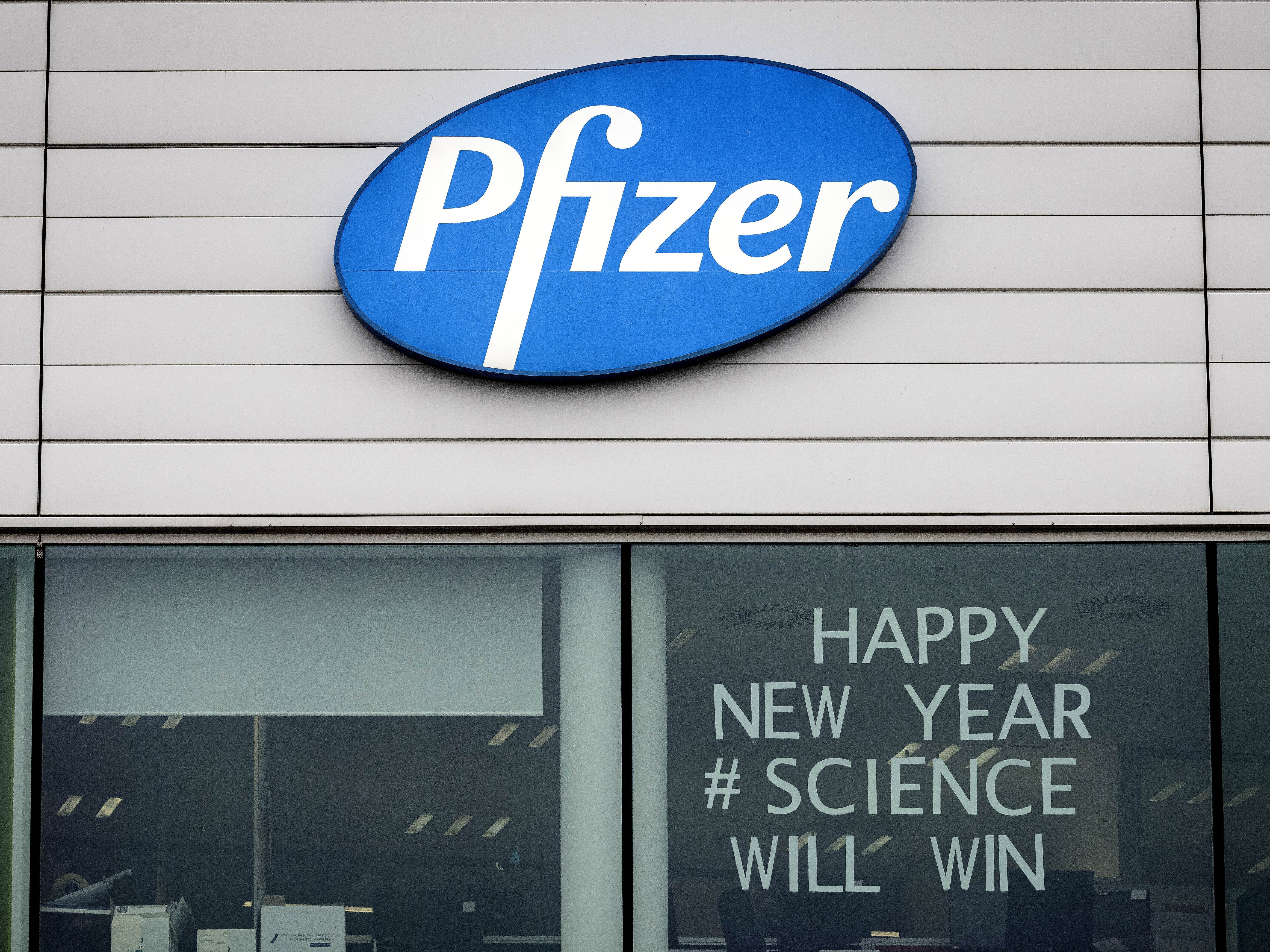 caption: A sign is shown in the window of an office at Pfizer Manufacturing in Puurs, Belgium, on Monday, the same day the European Medicines Agency authorized the use of the company's COVID-19 vaccine.
