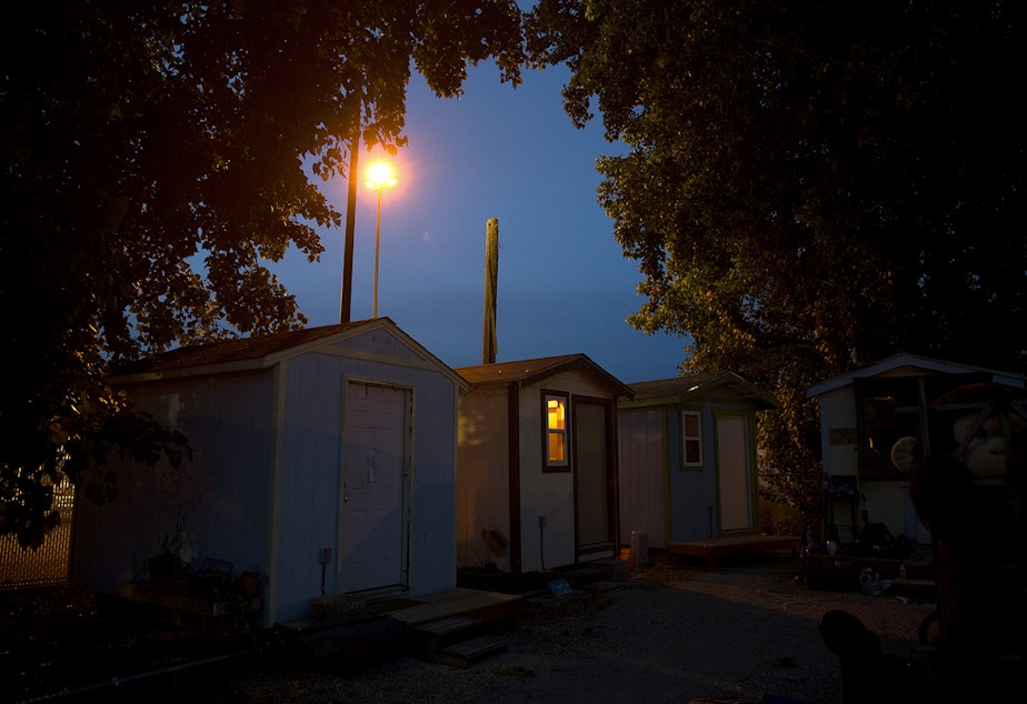 caption: A tiny house is lit up as the sun goes down on Sunday, June 9, 2019, at the Georgetown tiny house village in Seattle.
