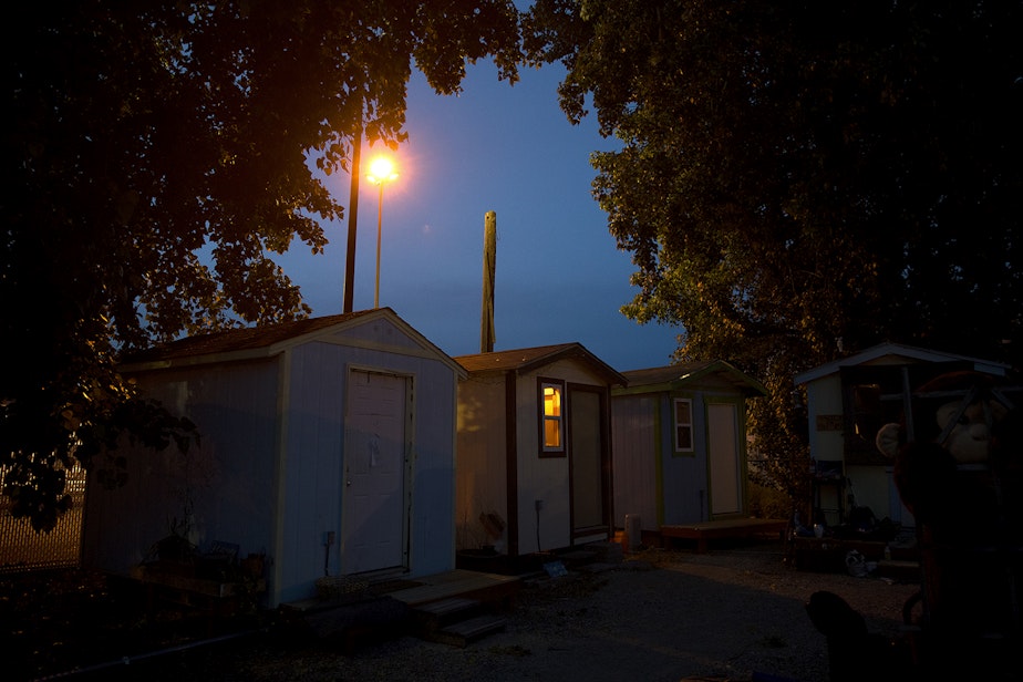 caption: A tiny house is lit up as the sun goes down on Sunday, June 9, 2019, at the Georgetown tiny house village in Seattle. 