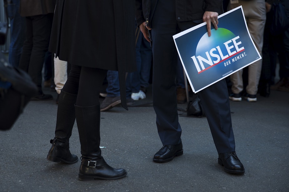 caption: Attorney General Bob Ferguson, right, holds an Inslee Our Moment sign after Governor Jay Inslee announced his candidacy for president on Friday, March 1, 2019, at A&R Solar on Martin Luther King Jr. Way in Seattle. 
