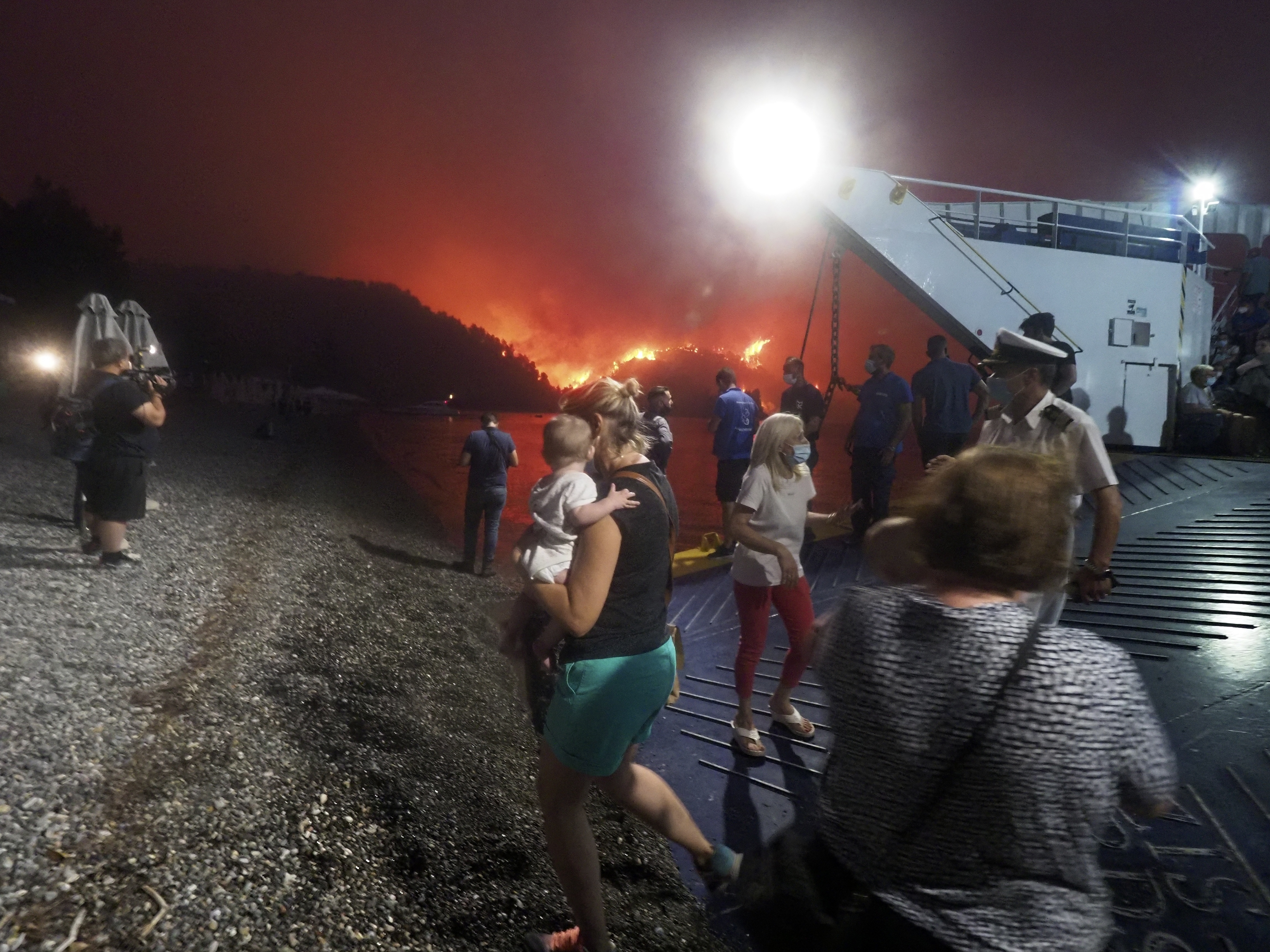 caption: People evacuate from a wildfire north of Athens, Greece, on Friday. A climate-driven heat wave helped create conditions for the fire to burn out of control. Scientists warn that humans are running out of time to curb greenhouse gas emissions and avoid catastrophic global warming.