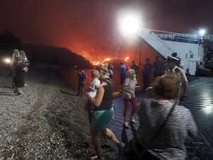 caption: People evacuate from a wildfire north of Athens, Greece, on Friday. A climate-driven heat wave helped create conditions for the fire to burn out of control. Scientists warn that humans are running out of time to curb greenhouse gas emissions and avoid catastrophic global warming.