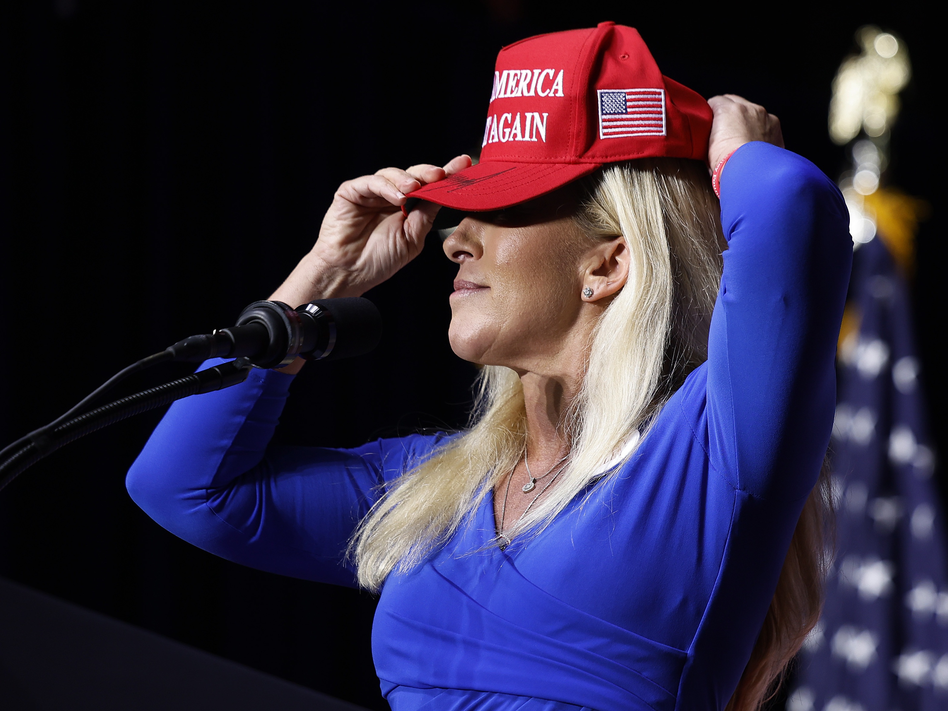 caption: In this file photo, then-Rep. Marjorie Taylor Greene (R-GA) puts on her Make America Great Again hat while addressing a campaign rally with then Republican presidential candidate and former President Donald Trump March 9, 2024 in Rome, Georgia. After Trump ordered strikes on Iran March 1, 2026, Greene sharply criticized the president for abandoning "America First" foreign policy and his promises of "no new wars."