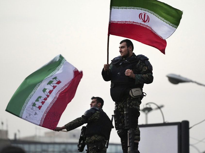 caption: Two anti-riot police officers wave the Iranian flags during a street celebration after Iran defeated Wales in Qatar's World Cup, at Sadeghieh Sq. in Tehran, Iran, Friday, Nov. 25, 2022.