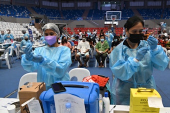 caption: Health workers prepare COVID-19 vaccines at a coliseum in suburban Manila on November 29 — part of a massive 3-day vaccination drive launched by the government. It was one of 8,000 vaccination centers set up during the drive.