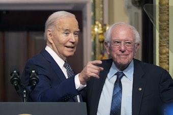 caption: President Biden stands with Sen. Bernie Sanders, I-Vt., on April 3, 2024. Four years ago, Sanders endorsed Biden, and the former rivals worked together to craft policy proposals that bridged Democratic divides.