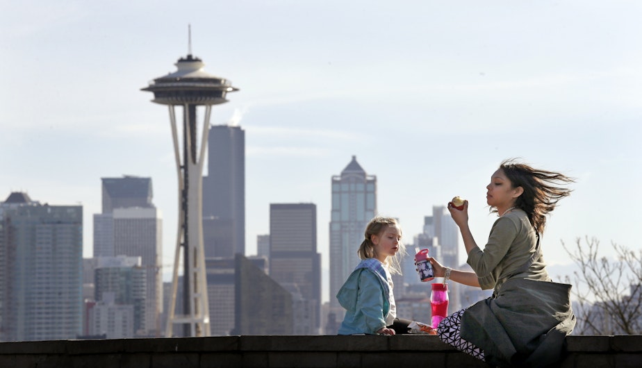 caption: Nora Kennelly, 3, picnics with her nanny, Ty Messiah, in the sun atop a wall overlooking the Space Needle and downtown Seattle, Monday, Feb. 8, 2016. 