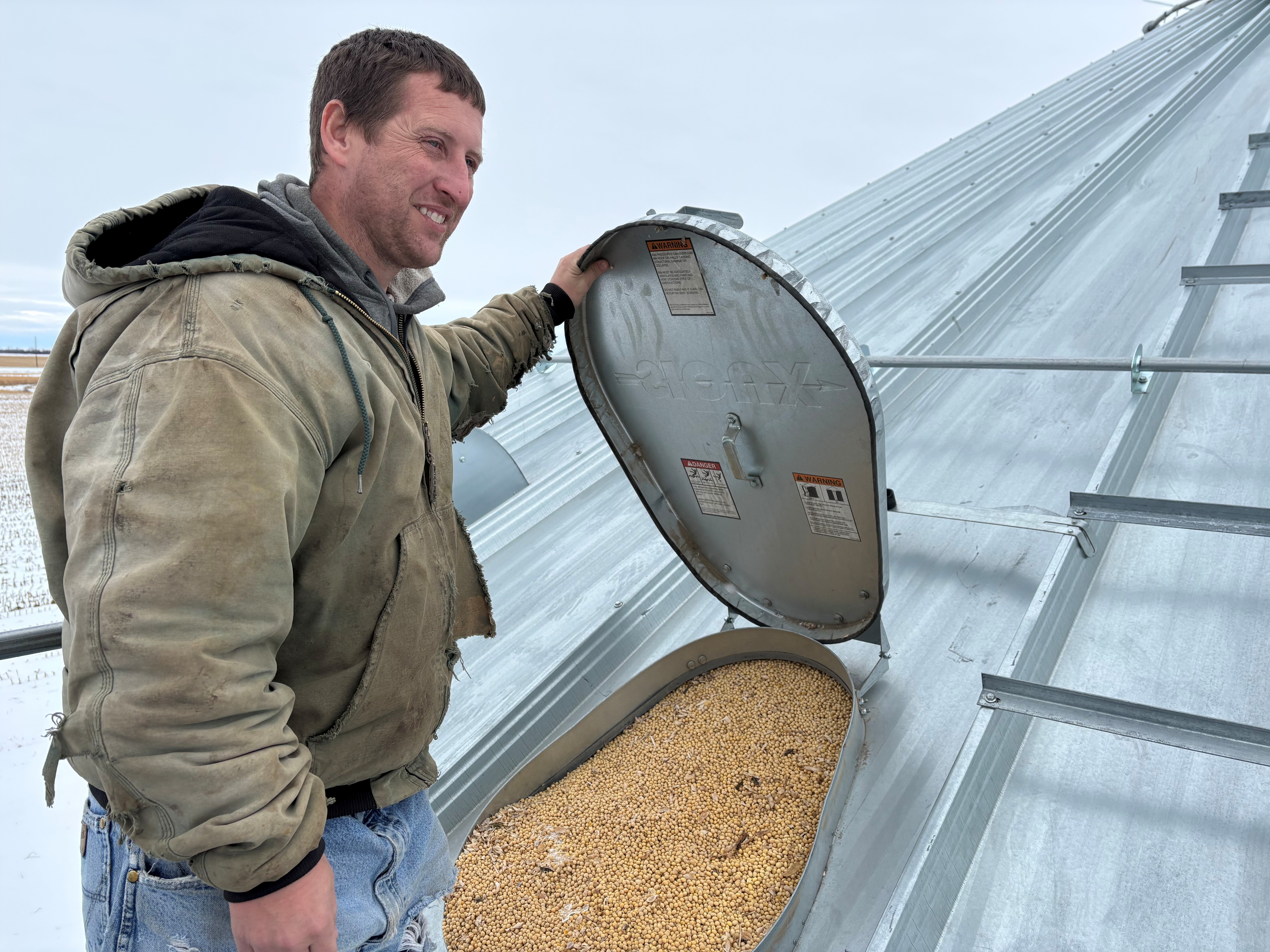 caption: Soybean farmers like Kevin Deinert in South Dakota have grain bins full of unsold beans they were planning to send to China before President Trump initiated a trade war with that country. China has recently started buying U.S. soybeans again, but in much smaller quantities than before.