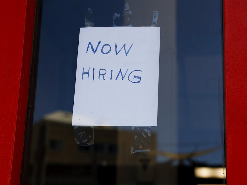 caption: A "Now Hiring" sign is displayed on a storefront in the Adams Morgan heighborhood in Washington, D.C., on Oct. 07, 2022 .