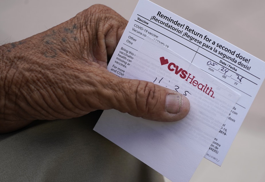 caption: A man holds his vaccination reminder card after having received his first shot at a pop-up vaccination site next to Maximo Gomez Park, also known as Domino Park, on May 3, 2021, in the Little Havana neighborhood of Miami.