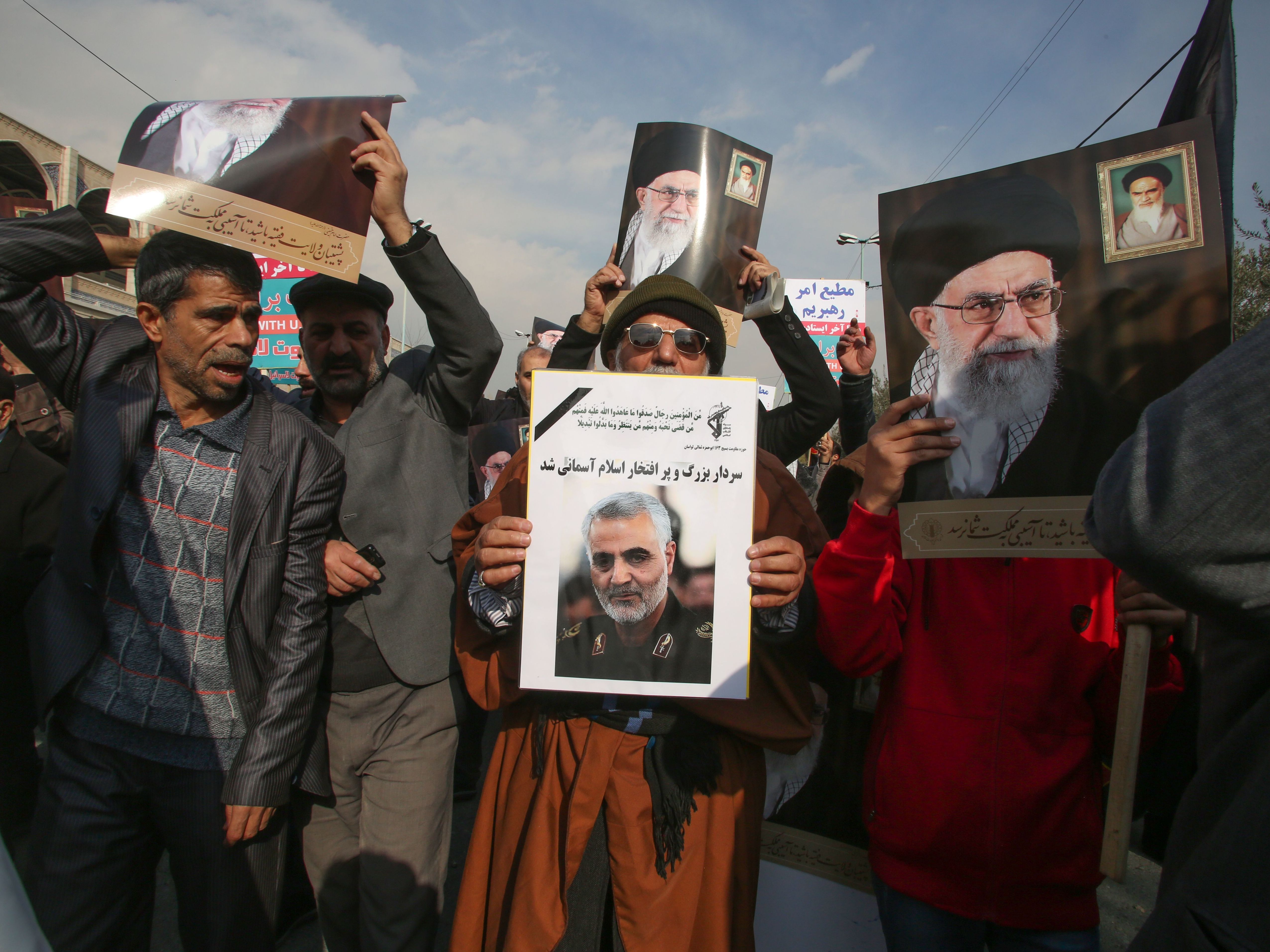 caption: Iranian demonstrators holds posters of slain Gen. Qassem Soleimani (center) and the country's supreme leader, Ayatollah Ali Khamenei, during a rally Friday in the capital, Tehran. The U.S. strike on the military leader in Baghdad has elicited warnings of retaliation from Iran.