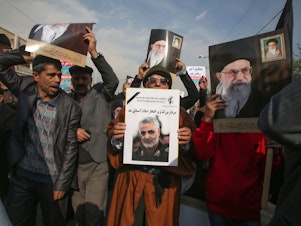 caption: Iranian demonstrators holds posters of slain Gen. Qassem Soleimani (center) and the country's supreme leader, Ayatollah Ali Khamenei, during a rally Friday in the capital, Tehran. The U.S. strike on the military leader in Baghdad has elicited warnings of retaliation from Iran.
