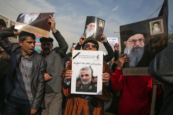 caption: Iranian demonstrators holds posters of slain Gen. Qassem Soleimani (center) and the country's supreme leader, Ayatollah Ali Khamenei, during a rally Friday in the capital, Tehran. The U.S. strike on the military leader in Baghdad has elicited warnings of retaliation from Iran.