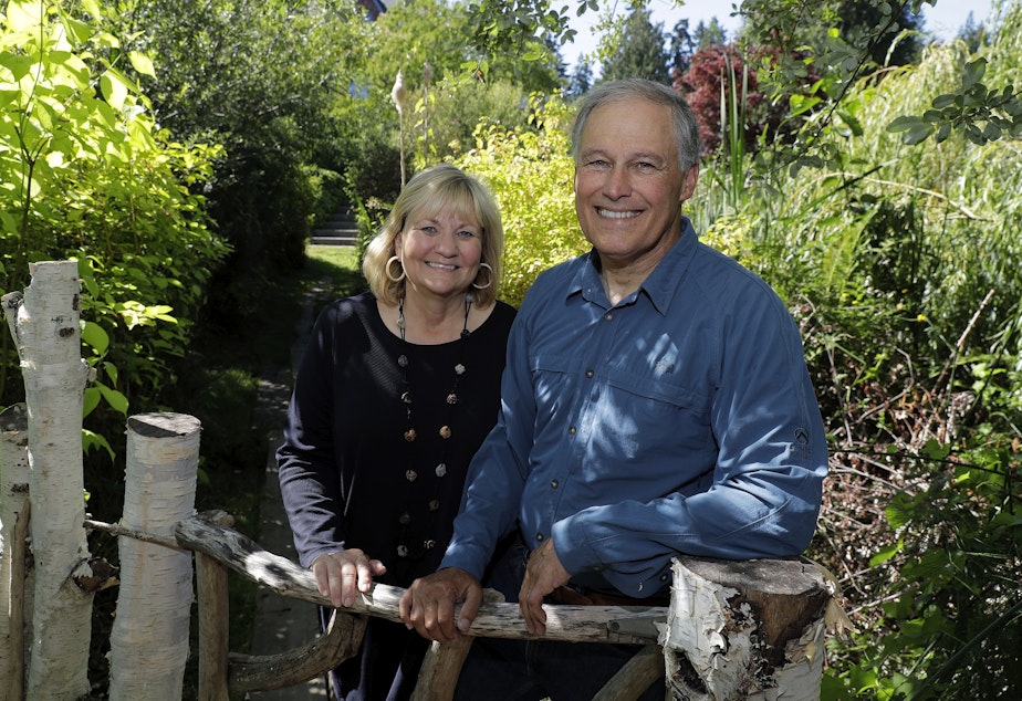 caption: In this July 23, 2018 photo, Washington Gov. Jay Inslee, poses for a photo with his wife Trudi Inslee, at their home on Bainbridge Island, Wash. 